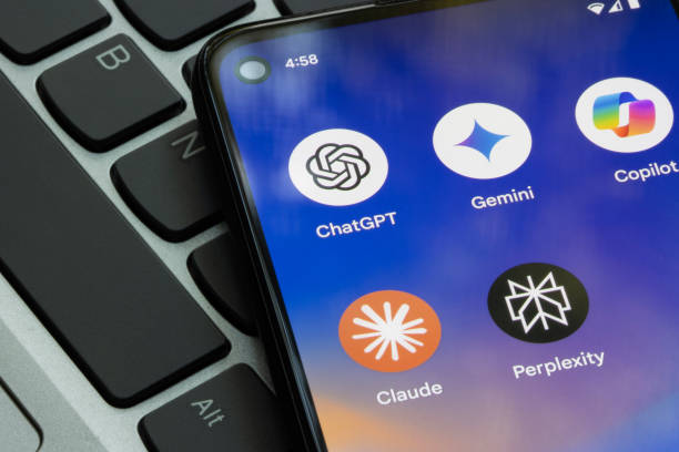 A smartphone resting on a laptop keyboard displaying icons for consumer generative AI apps like ChatGPT, Gemini, and Claude, which frequently contribute to Shadow AI risks in the workplace.