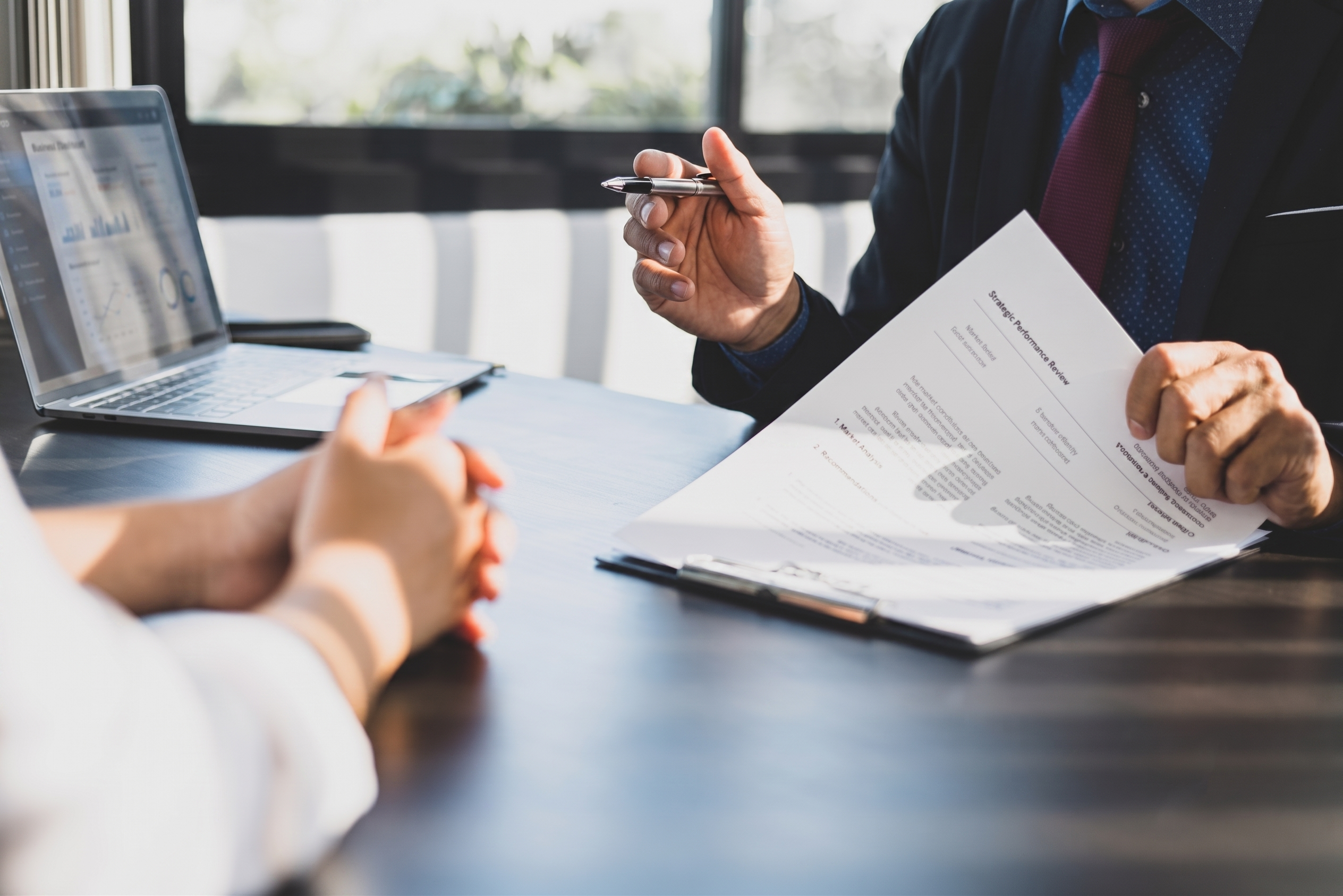 Two business professionals sitting across from each other at a desk, reviewing a document and negotiating software pricing to mitigate costs from senate bill 122.