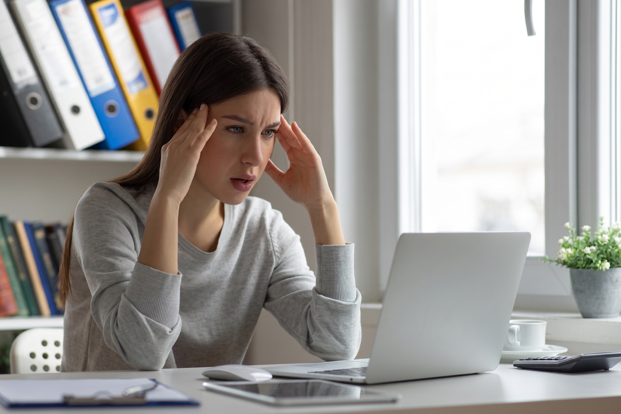 Stressed employee reviewing a laptop after encountering a suspicious social engineering scam.